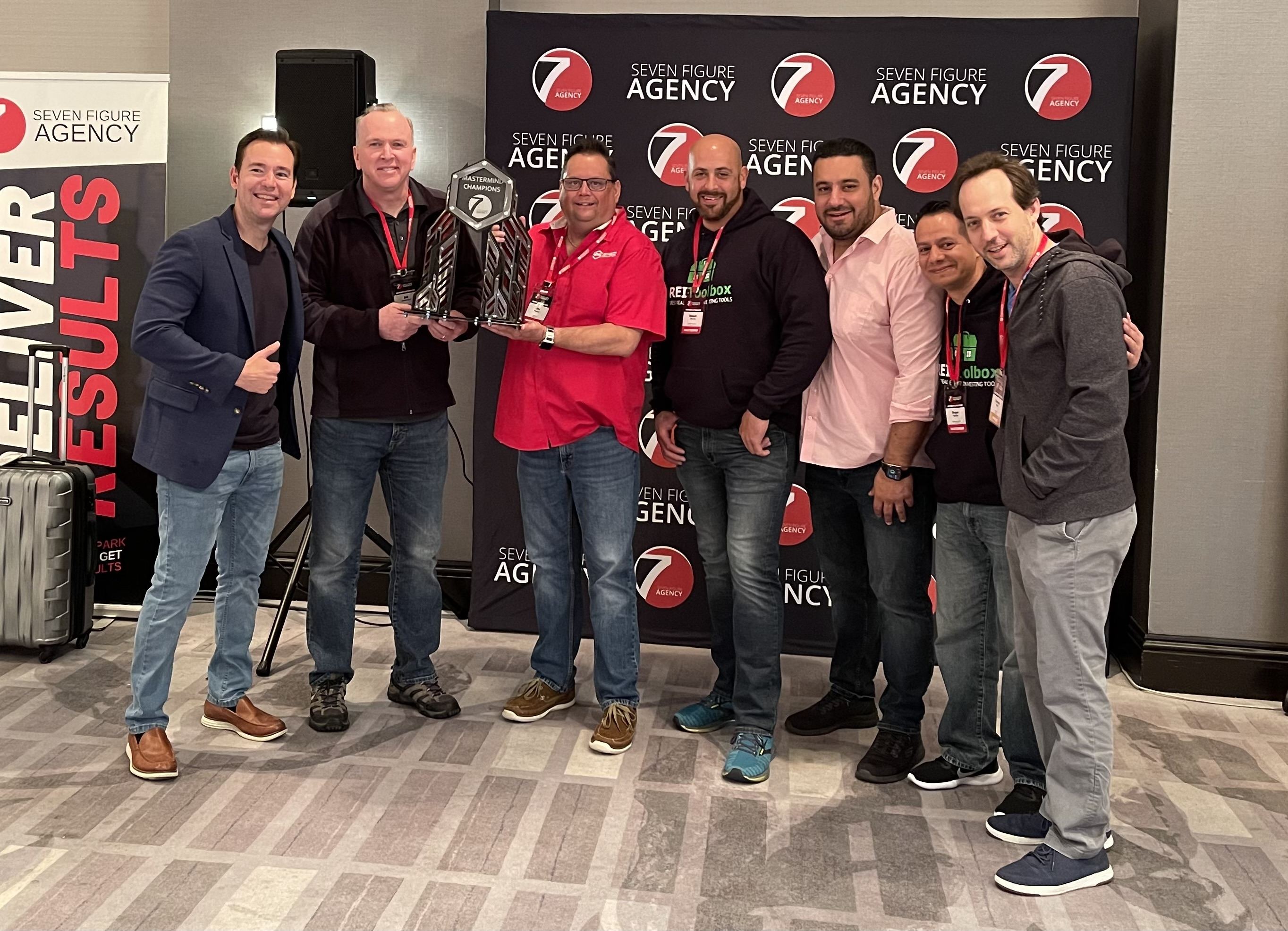 Jim Mosier with his Seven Figure Agency mastermind group, holding the Mastermind Champions trophy